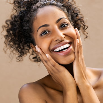 Woman smiling with her hands on her face